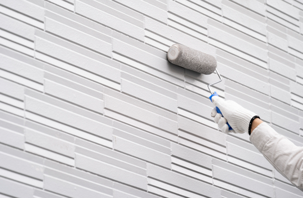 外壁をローラーで塗装している様子