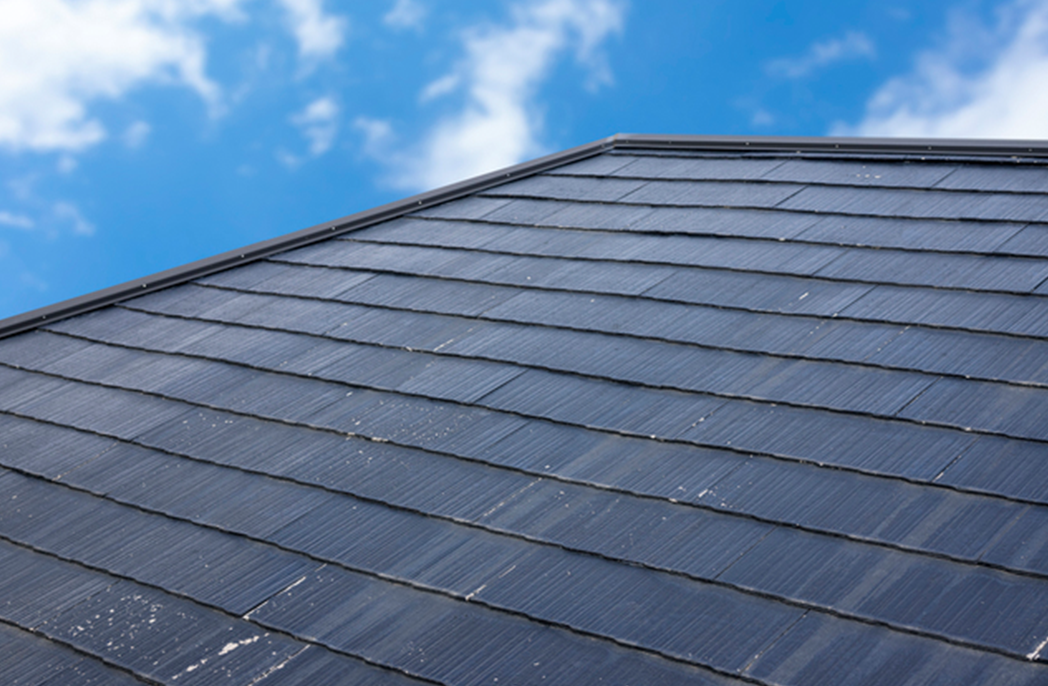 青空の下にある屋根の塗装作業